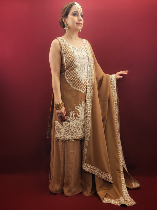 Discover this luxurious and exclusive sharara dress. Made from Golden Brown georgette, this dress features intricate thread-work on the kameez and a stunning dupatta. Perfect for any party or festive occasion, it will make you stand out with its elegant and tasteful design. Elevate your wardrobe with this masterpiece.